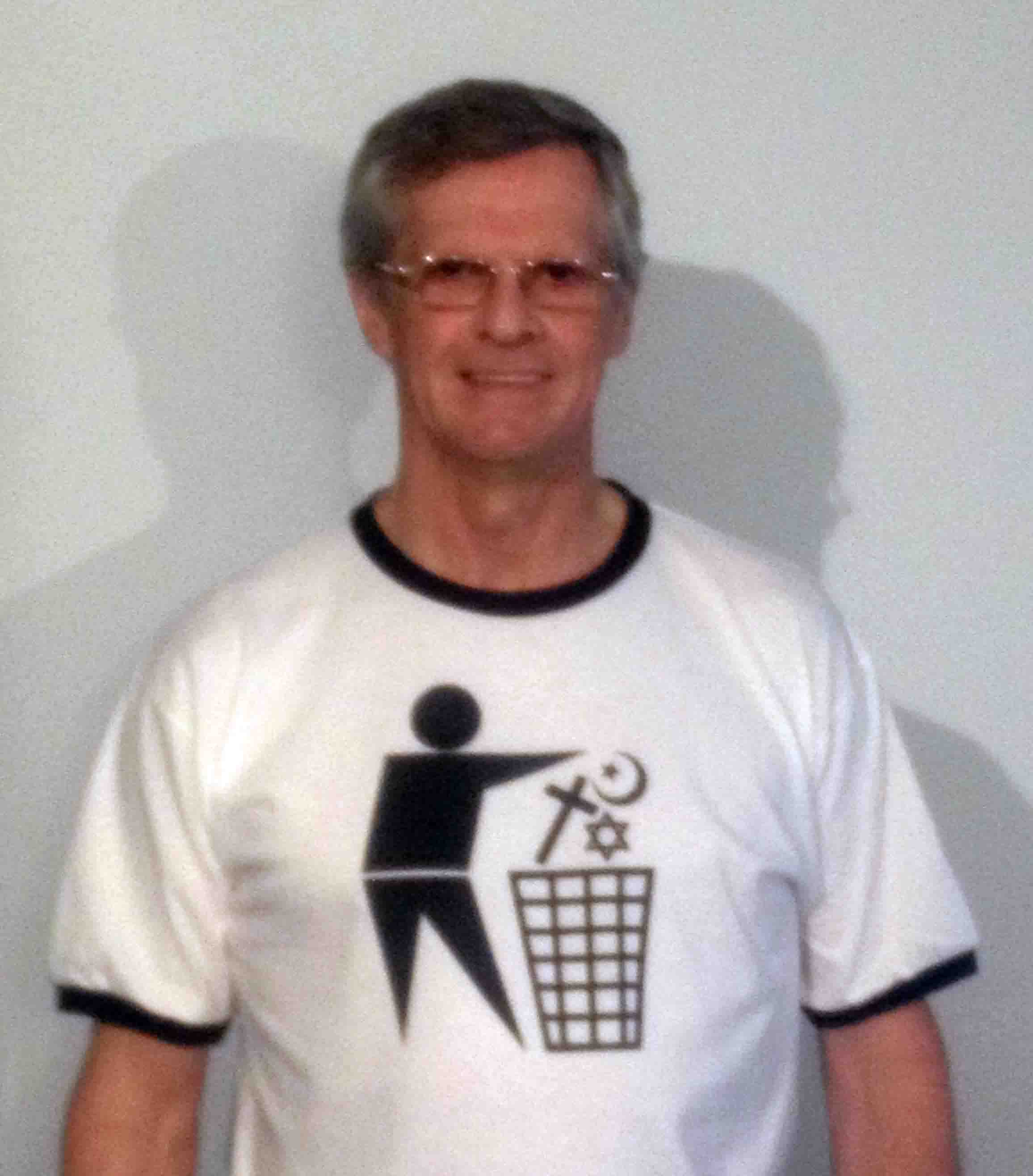 Darwin Bedford wearing a T-shirt depicting the international symbol for a wastes container with religious symbols in place of the wastes. 