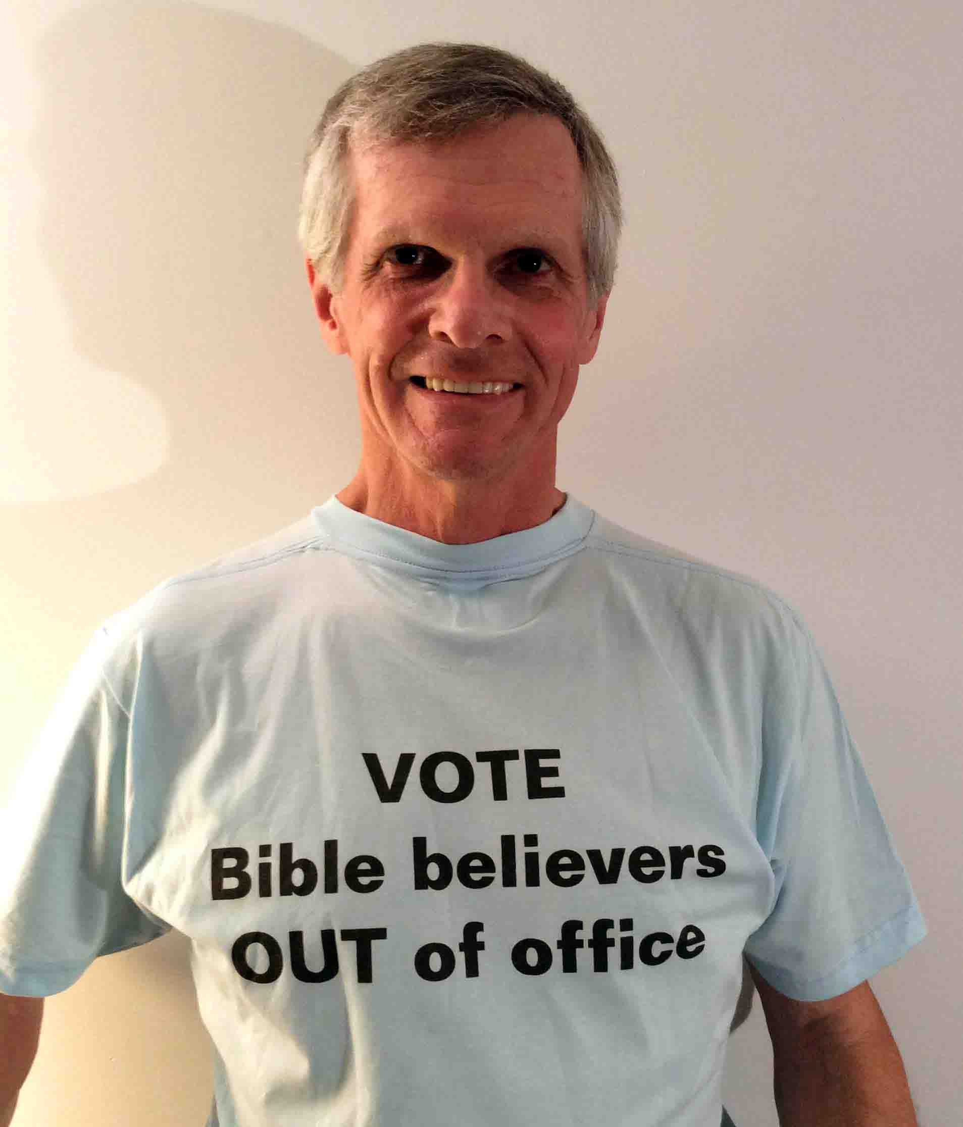 Darwin Bedford wearing his shirt that says 'Vote Bible believers OUT of office'