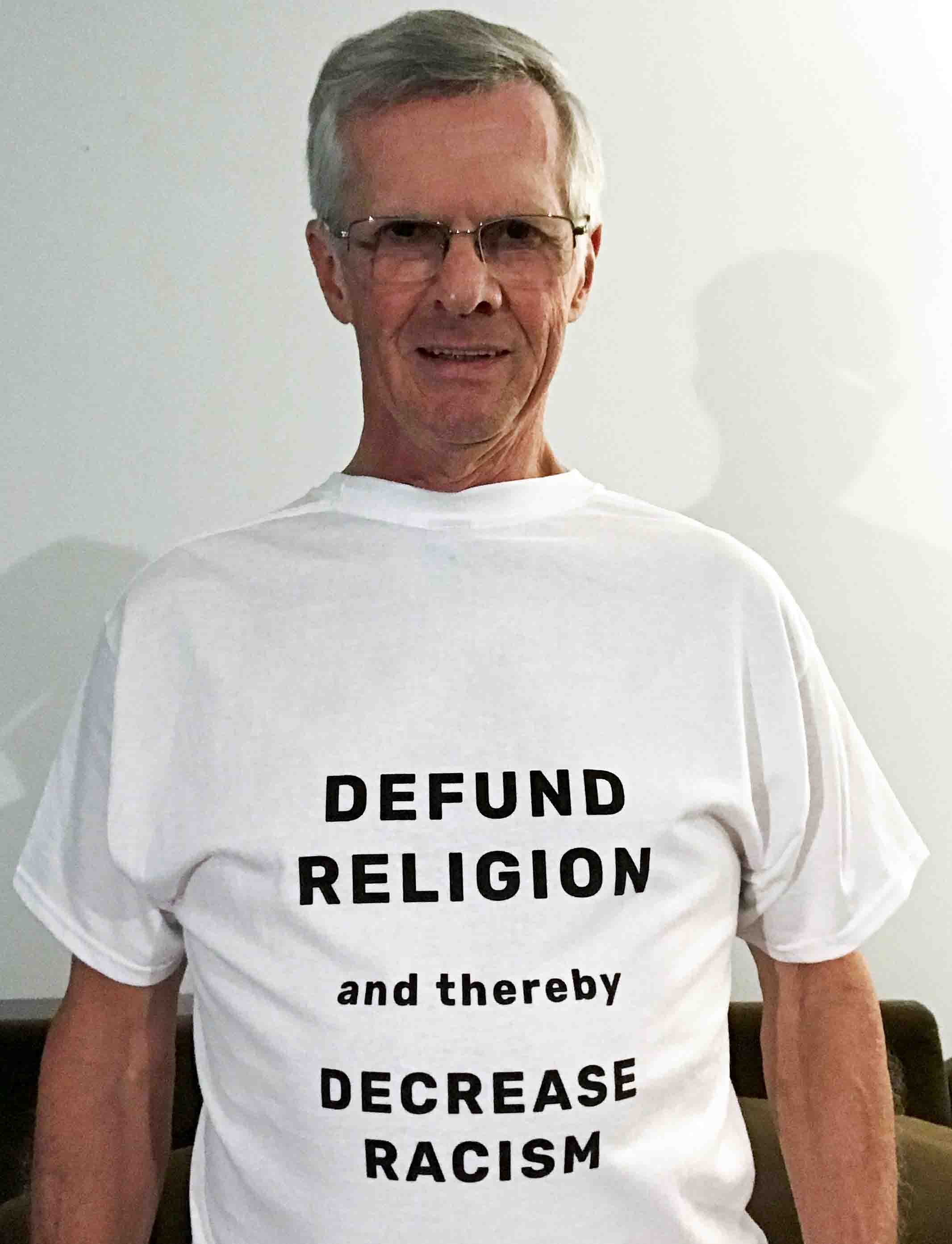 Darwin Bedford wearing his shirt that says 'DEFUND RELIGION and thereby DECREASE RACISM'