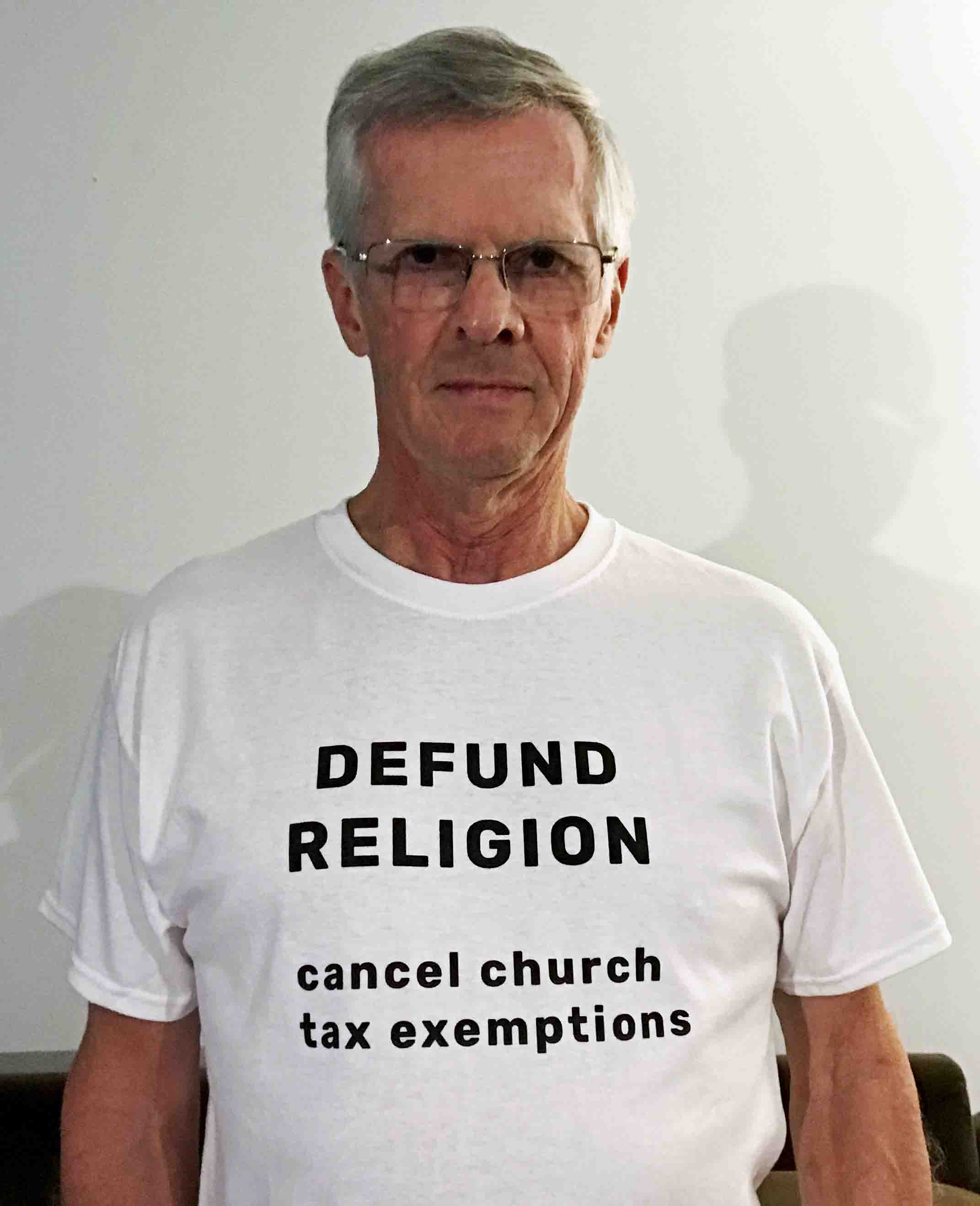 Darwin Bedford wearing his shirt that says 'DEFUND RELIGION cancel church tax exemptions'